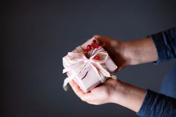 Girl holding a gift box on a dark gray background	