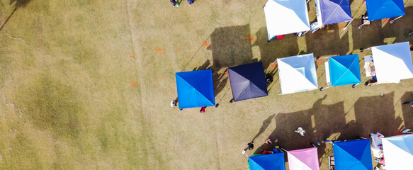 Panoramic top view colorful tents of farmer market vendors at large square lawn in downtown...