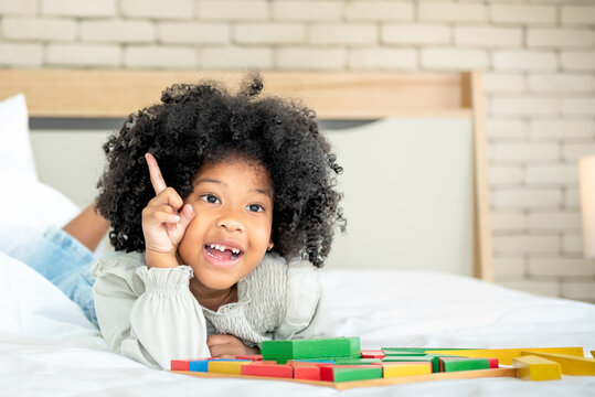 Portrait images of African American 5 year old with broken tooth and curly hair, Lying in white bed with happy and relax, to African child concept.