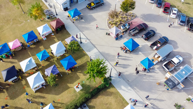 Aerial view busy parking lot near row of colorful tents with people shopping at farmer market near Dallas, Texas, USA