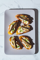 Toast with cream cheese, sprats (sardine) and green onions. Simple homemade recipes concept.