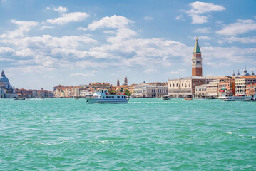 Cruise ship sailing on sea water surface with city buildings in the background against cloudy sky
