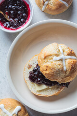Traditional Easter cross buns with raisins, butter and jam on gray background.