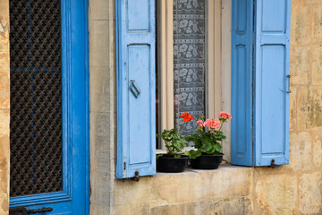 Monpazier, France. June 2016. Close up of a front door and window with begonias in the frame.