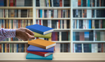 hand holding book in front of blurry library background