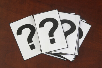 Many cards with question marks on wooden table.