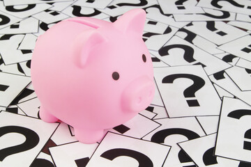 Pink piggy bank on question marks. Saving money problems and solutions concept.