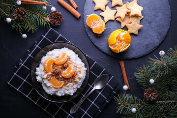 Obraz na płótnie Canvas Christmas rice pudding with cinnamon and tangerines on black background