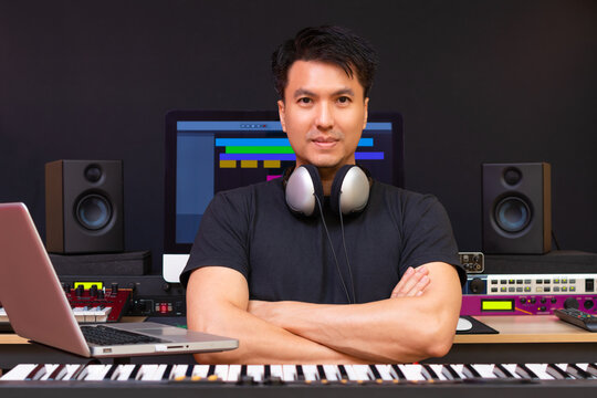 portrait of smiling asian professional music producer, composer, sound engineer, arranger in recording studio
