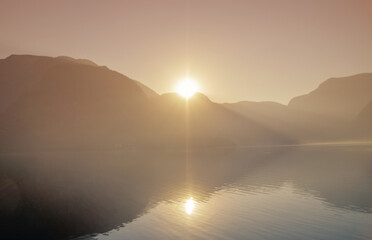 View of sunrise over Alps in Hallstatt covered by fog during golden hour