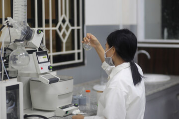 Asian woman scientist checking laboratory glass flask to make an experiment in the laboratory