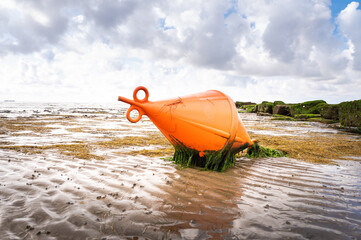 A bright red buoy lies on the mudflat in Dagebüll in Schleswigholstein at low tide
