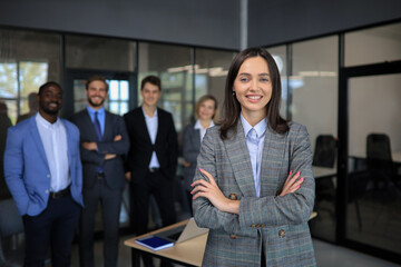 Business woman with her staff, people group in background at modern bright office indoors.
