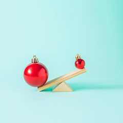 Creative New Year's layout with a wooden seesaw with two red New Year's baubles. Minimal Christmas...