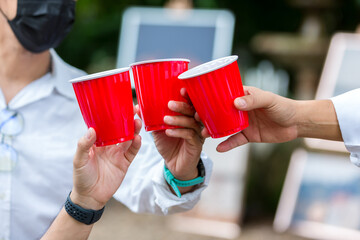 Friends clinking glass on alcohol on party. Friends relaxing with red cups of alcohol. celebration, friendship. Three friends having fun and drinking alcohol during New Year 2022 party 