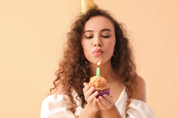 Beautiful African-American woman with Birthday cake on color background