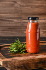 Bottle with organic tomato sauce on wooden background