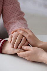 Young woman holding hands of grandmother at table