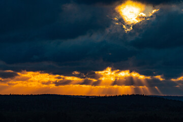分厚い暗雲から溢れる夕方の太陽光線