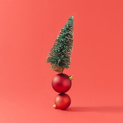 Creative composition made with Christmas tree and ornaments against red background. Minimal New Year celebration concept.