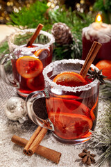 Christmas hot mulled wine with a slice of orange and spices. A glass cup with a hot traditional drink on a snowy background in festive decorations. Evening mood and decoration 