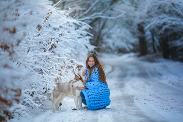 A woman with a purebred husky dog on a snowy forest road