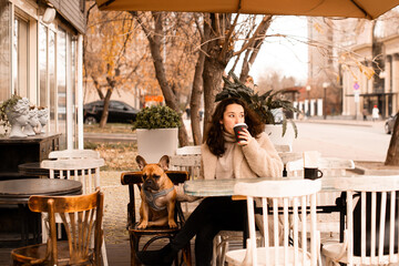 Young brunette woman with her pet french bulldog in coffee shop