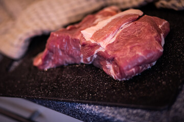 a piece of meat, pork meat on a cutting board, raw red meat, fresh meat on the kitchen table