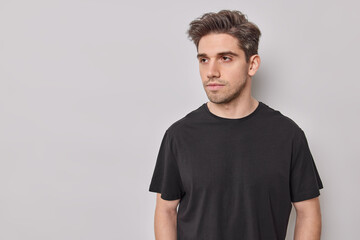 Indoor shot of determined serious European man concentrated away has deep thoughts dressed in...