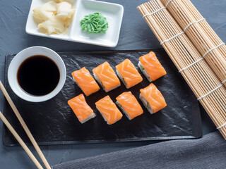 Philadelphia sushi rolls on a black textured plate stand on a gray background. Top view, flat lay. Japanese cuisine
