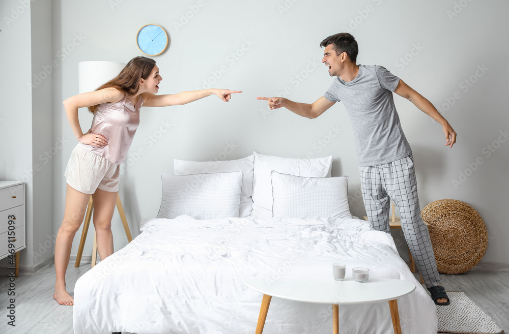 Poster angry young couple arguing in bedroom