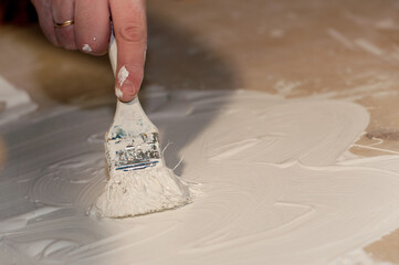 a man's hand paints the surface with a white paint brush