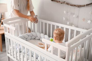 Mother playing with her cute little baby in crib