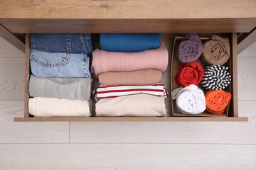 Open drawer with folded clothes indoors, top view. Vertical storage