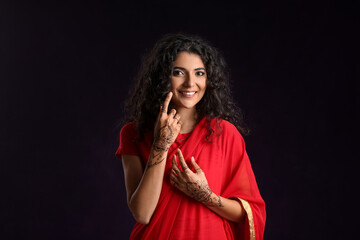 Beautiful Indian woman with henna tattoo on dark background