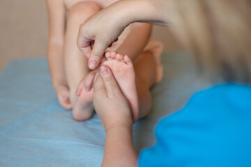Little baby feet in the hands of the masseur. Close-up. Massotherapy. Copyspace.