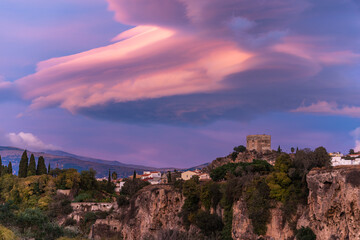 View at sunset of the Velez de Benaudalla cliffs with its castle at the top, with colorful clouds from the afternoon sun.