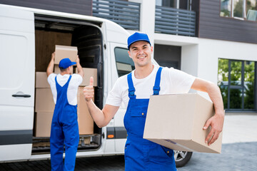 Two removal company workers unloading boxes from minibus into new home