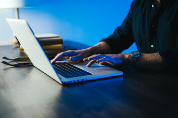 Close-up of male hands with laptop. Man is working remotely at home. Freelancer at work