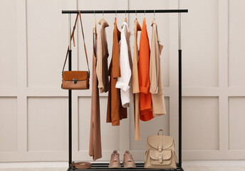 Fototapeta na wymiar Rack with stylish women's clothes, shoes and accessories near light wall