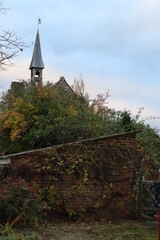 overgrown green garden looking up to a village church spire