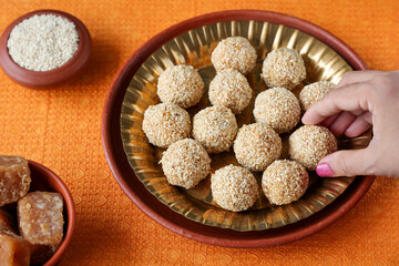 Til ladoo laddu woman hand take white sesame ladoo ellu urundai Indian festival food snack sweet Lohri Makar Sankranti Pongal Diwali harvest festival Tamil Nadu winter festival Punjab North India 