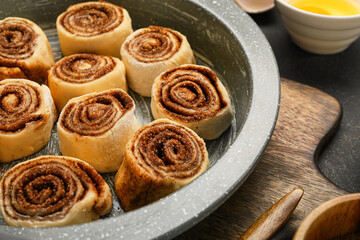 Obraz na płótnie Canvas Baking dish of uncooked cinnamon rolls on black background, closeup