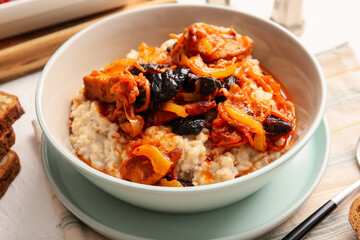 Tasty oatmeal and beef stew with prunes on light table, closeup