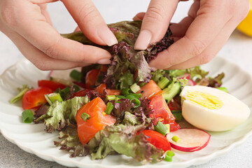 Woman preparing delicious salad at table, closeup