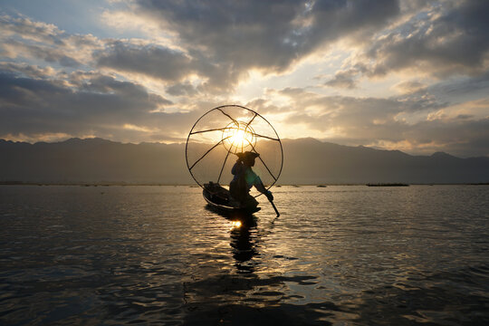 silhouette of local fisherman using coop to catching in inle lake at sunrise - Powered by Adobe