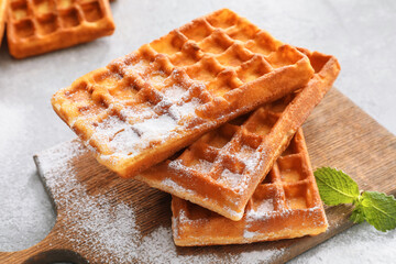 Board with delicious Belgian waffles and mint on light background, closeup