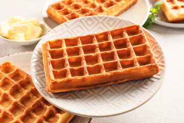 Plates with tasty Belgian waffles on light background, closeup