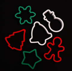 Naklejka premium Multi-colored plastic cookie cutters for New Year's theme on a dark background.