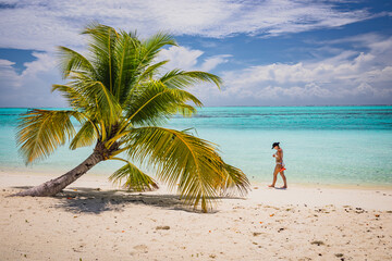 Fototapeta na wymiar The girl is walking on a paradise island with turquoise water and exotic vegetation - the Maldives